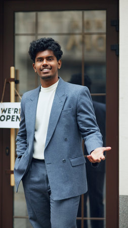 Proud entrepreneur standing outside entrance of his new store, cafe, shop, welcoming customers with...
