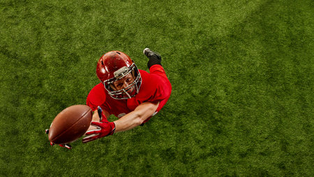 Top view image of concentrated man, American football player in red uniform in motion on stadium,...
