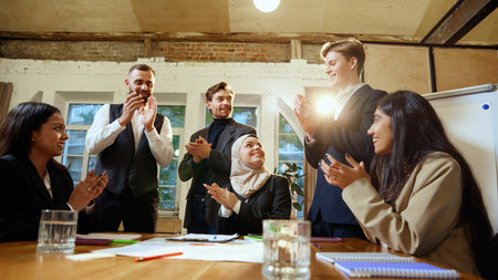 Colleagues clap in appreciation after business presentation on global data trends. Young man explaining global market data with flipchart.の写真素材