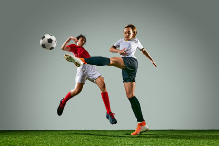 Competitive moment between two female soccer players in dynamic motion, kicking ball with focus. Rainy training sessionの写真素材