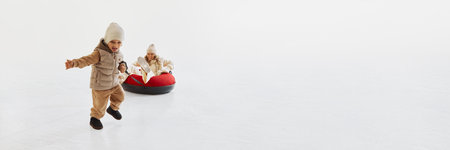 Young boy, child running excitedly and pulling his mother on snow tube, enjoying playful winter day together.の写真素材