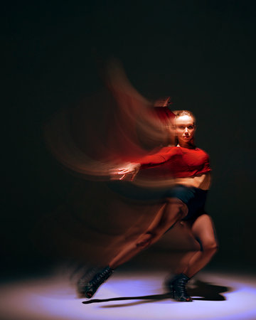 Creative design. Energetic and dynamic performance, young girl dancing with passion on dark background with abstract motion blur effectの写真素材