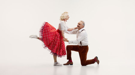 Elderly couple, dressed in vintage-inspired clothing, dances energetically retro dance isolated on white backgroundの写真素材