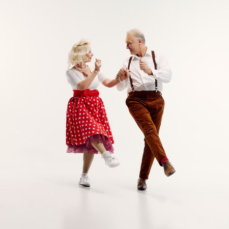 Elderly couple dancing together with smiles and enthusiasm isolated on white backgroundの写真素材