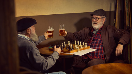 Relaxed bearded elderly men, friends meeting at warm lit bar, playing chess and drinking bar....