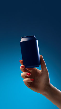 Woman hand holding deep blue aluminum beverage can for soda, beer, energy drinks, against vibrant...