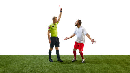 Young referee raising hand with red card to the male soccer player, symbolizing strict enforcement of soccer rules during matchの写真素材