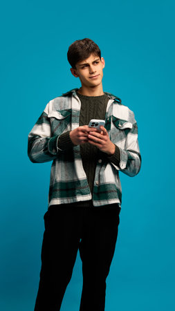 Portrait of young handsome man in casual clothes holding smartphone and texting message with...