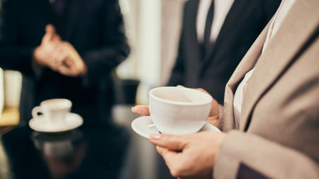 Close-up o professional holding coffee cup, symbolizing connection and communication during a networking event.の写真素材