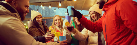 Group of friends enjoying winter gathering, raising colorful cups and glasses of mulled wine with orange slices in joyful toast.の写真素材