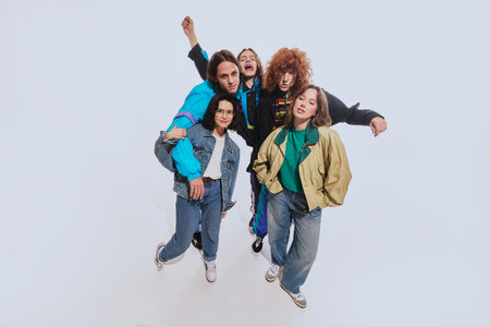 Five young stylish people, men and women in their 20s wearing stylish retro inspired outfits, posing...