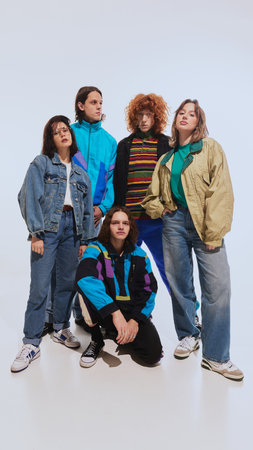 Five young stylish people, men and women in their 20s wearing stylish retro inspired outfits, posing against white studio backgroundの写真素材
