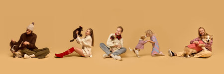 Cheerful group of people posing with their dogs, all dressed in warm, stylish winter outfits against a beige backgroundの写真素材