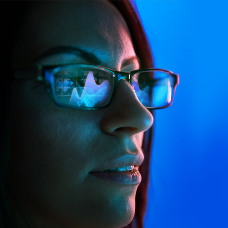 Close-up of woman wearing glasses reflecting bar charts and financial analytics, symbolizing technology and business decision-making.の写真素材