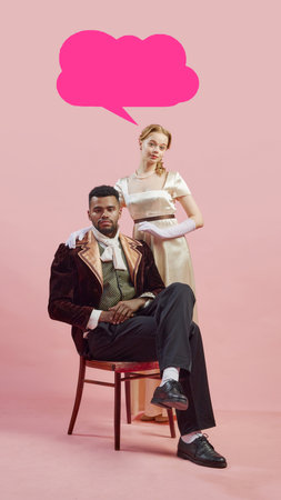Man in baroque-inspired velvet coat sitting with elegant woman standing by his side against pink background with pink speech bubble for text.の写真素材