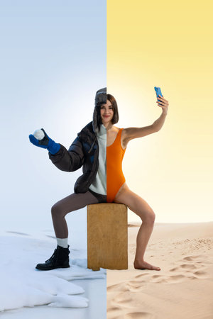Woman sitting on box, dressed half in winter clothing, half in summer swimsuit, holding snowball and...