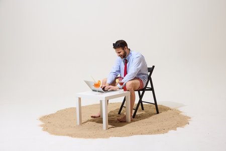 Man working on laptop at small table with cocktails, wearing sunglasses, formal shirt, tie, swim...