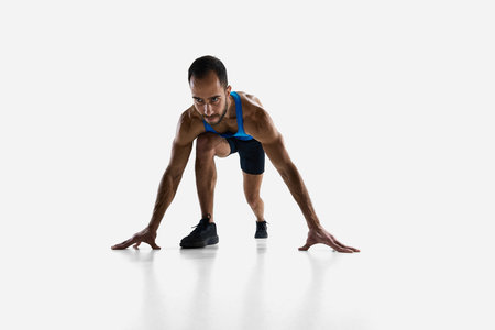 Focused and determined man, runner standing at starting line, ready to run and win isolated on white...