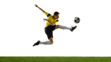 Side view dynamic image of man, soccer player in motion, kicking ball mid-air isolated on white background.の写真素材
