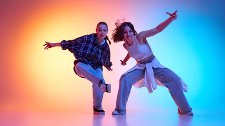 Expressive dancers dancing hip hop with energy and passion against gradient studio background in neon lightの写真素材