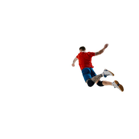 Back view image of determined athlete, male volleyball player dressed in red jersey and blue shorts, playing against white studio backgroundの写真素材
