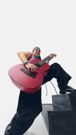 Powerful stage presence. Low angle view of female guitarist steps up onto black platform, playing...