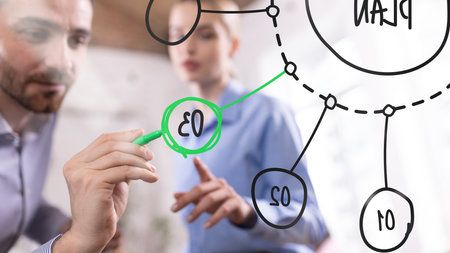 Professional teamwork visualizing business strategy, businessman marking key step with green marker,...