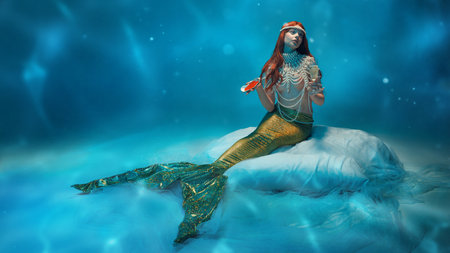 Mystical redhaired woman, mermaid holding seashell, savoring champagne in dreamy underwater world.の写真素材