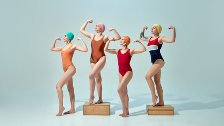 Group of strong women in swimsuits posing like vintage superheroes with flexed arms against light blue background. Champions.の写真素材