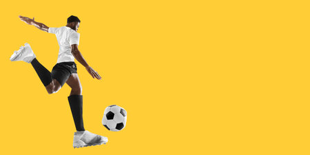 Man, soccer player in white uniform preparing to strike ball on bold yellow background in creative cut-out collage styleの写真素材