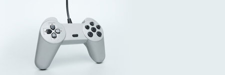 Close-up of retro wired video game controller against pale background symbolizing classic gaming...