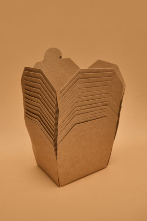 Stacked kraft paper food boxes against light brown background. Concept of packaging, delivery, recycling, eco materials.の写真素材