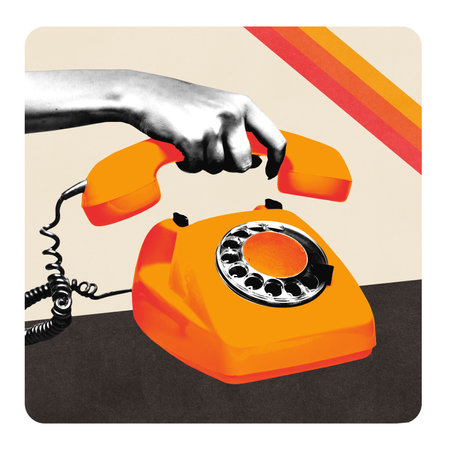 Hand grabs handset of orange rotary phone with bold dial and cord on minimal background.の写真素材
