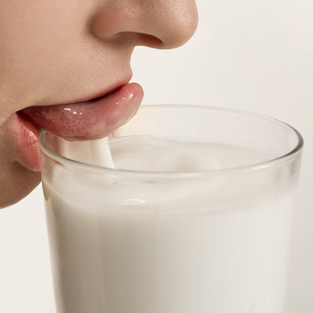 Lips gently press into milk surface creating soft ripple and subtle motion Concept of drink aesthetics advertisementの写真素材