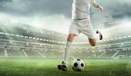 Cropped image of soccer player in white uniform kicking ball during intense outdoor match in 3D rendered stadium full of fans.の写真素材