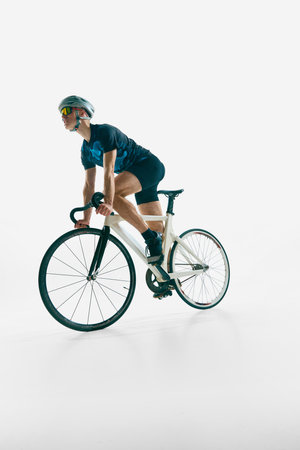 Low angle dynamic image of focused man, cyclist in full gear in motion, cycling, training isolated on white background.の写真素材
