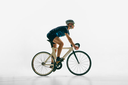 Side view image of young concentrated man, professional cyclist in motion on bicycle, riding isolated on white background.の写真素材