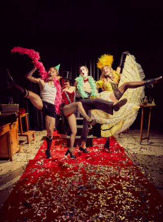 Group of four cabaret performers striking dynamic pose on red carpet with dramatic expressions and stage props.の写真素材