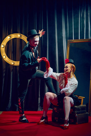 Elegant cabaret duo in top hats posing in smoke and spotlight on stage with romantic dramatic flair.の写真素材