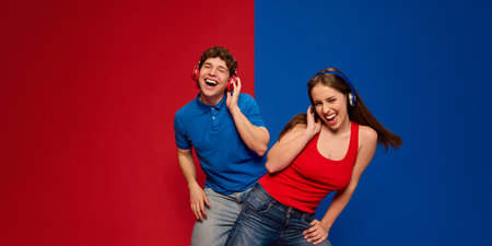 Happy, smiling young man and woman, couple wearing headphones and laughing, listening to music and dancingの写真素材