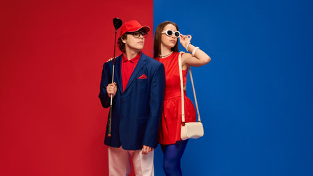 Man with golf club and woman adjusting sunglasses standing together with stylish expression on split red blue background.の写真素材