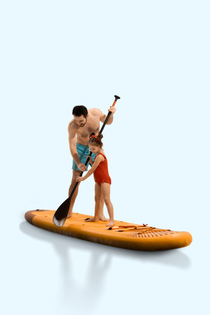 Father teaches daughter how to paddleboard, standing on orange sup board during summer holiday, isolated on light backgroundの写真素材