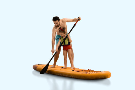 Father helps daughter learn paddling technique on sup board, exploring and learning against light studio background. Composite image.の写真素材