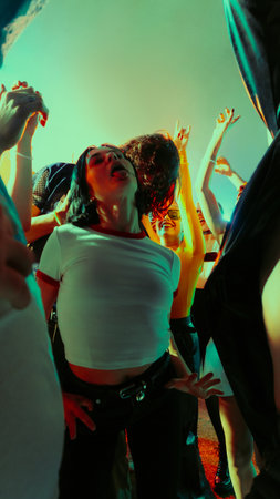Group of people dancing energetically at a party with vibrant lighting.の写真素材