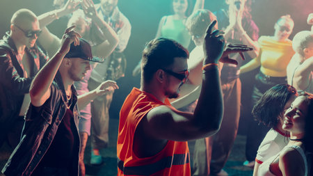 A lively scene of diverse people dancing at a vibrant nightclub with colorful lighting.の写真素材