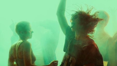 Silhouetted people dancing in a vibrant, colorful party atmosphere.の写真素材