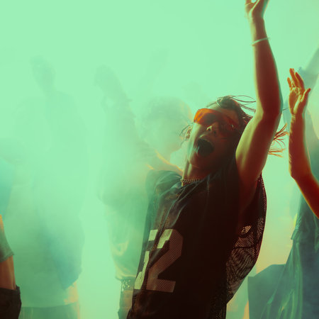 Dynamic group dance party. Vibrant lighting with people celebrating.の写真素材