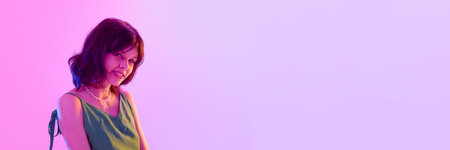 Happy girl smiling brightly showing pearl necklace under pink and violet neon light. Banner with...