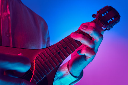 Musician pressing strings on mandolin neck in colored neon lighting with visible fret markers...