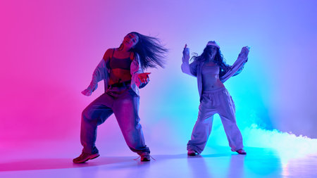 Creative female dancers show playful coordination in colorful fog-filled space during hip hop...